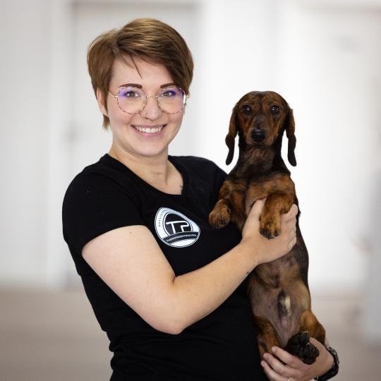 kurzhaarige, lachende Frau mit Dackel auf dem Arm